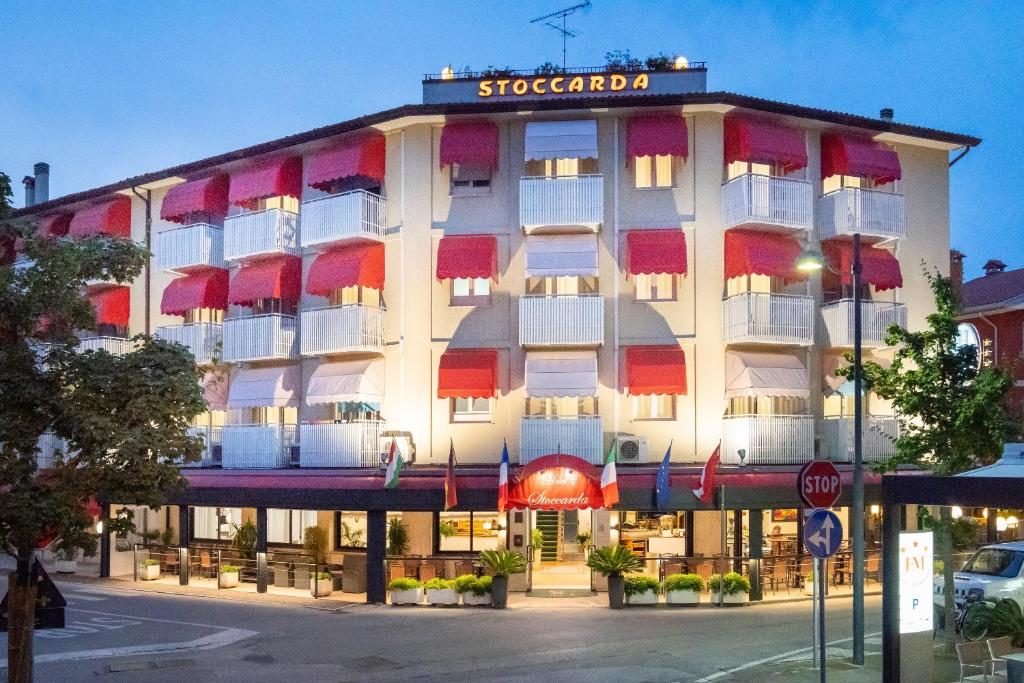a building with red and white balconies on a street at Hotel Stoccarda in Caorle