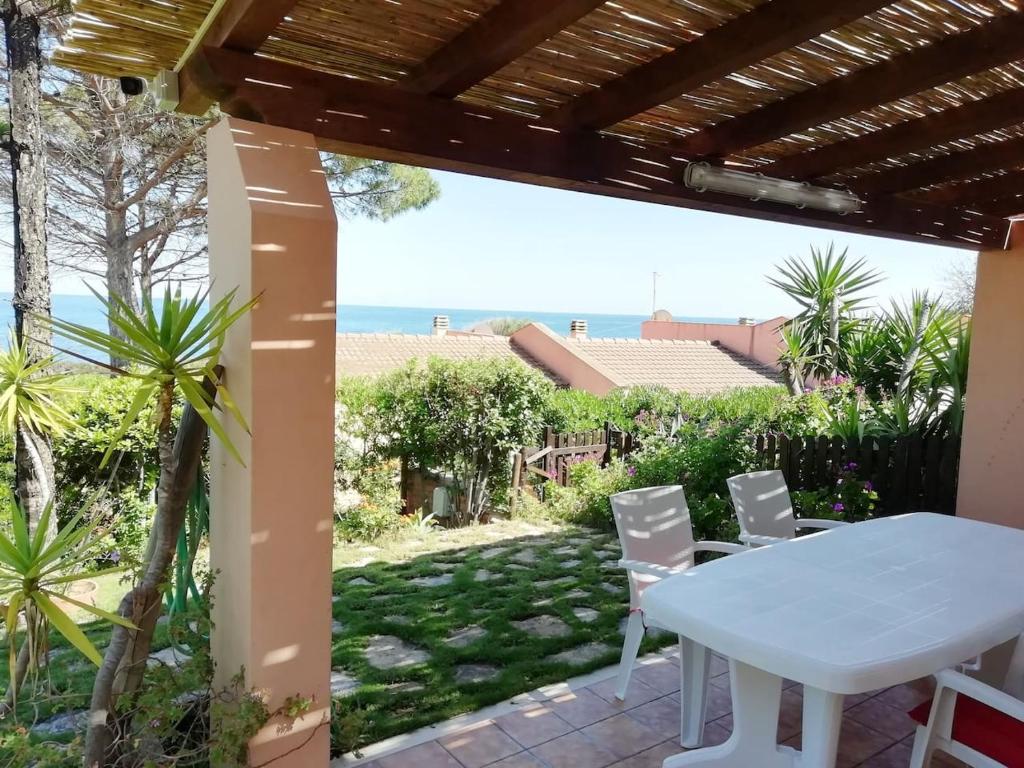 a table and chairs on a patio with a view of the ocean at "Ruby Seadragon Holiday Home" a 80 m dal mare con giardino recintato P5584 in Villaputzu