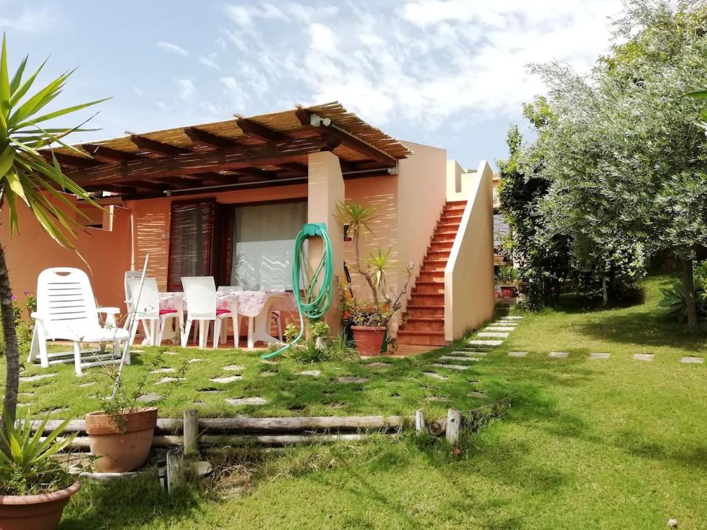 una casa con mesa y sillas en un patio en "Ruby Seadragon Holiday Home" a 80 m dal mare con giardino recintato P5584, en Villaputzu
