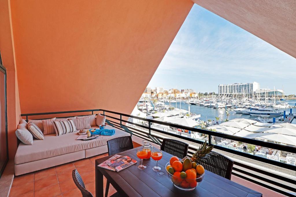 a balcony with a couch and tables and a view of a harbor at Marina Princess in Vilamoura