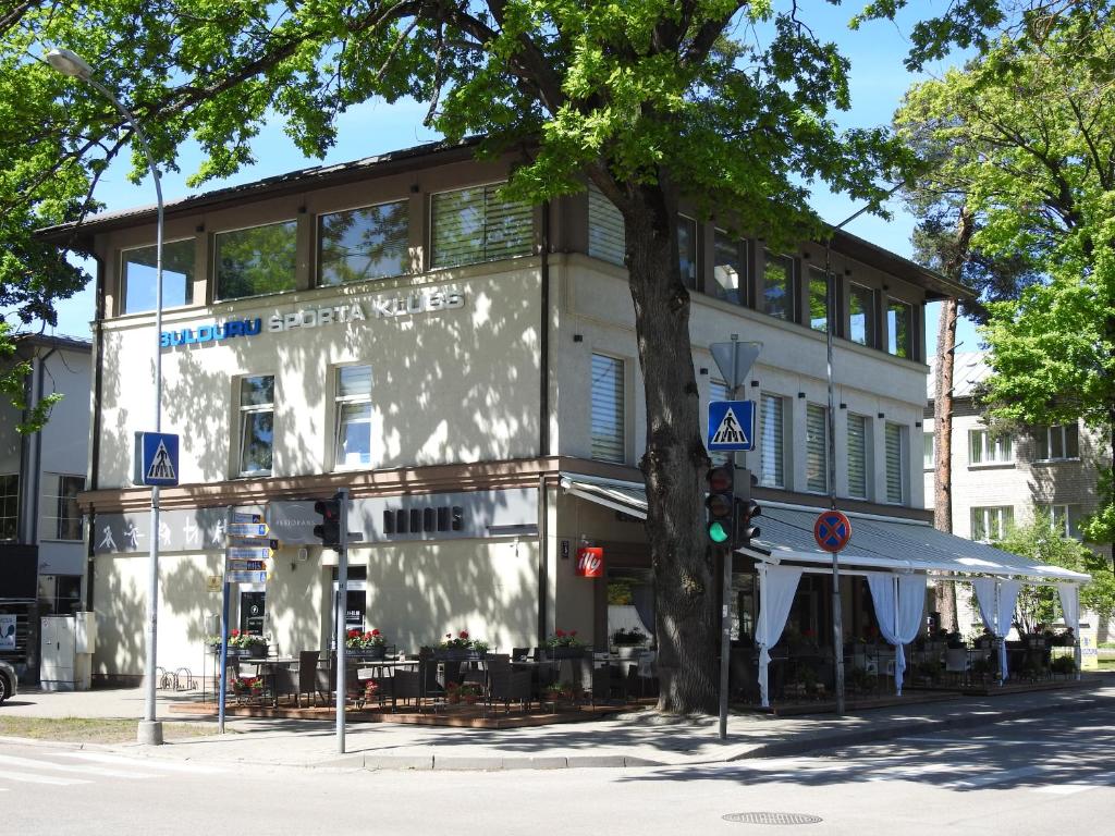 un edificio con un árbol delante de él en Vienibas prospekts 6, en Jūrmala