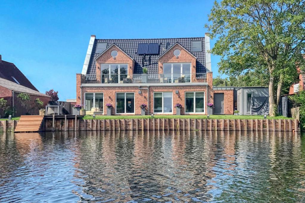 ein Haus auf dem Wasser vor einem Gebäude in der Unterkunft Seeblick-Norddeich in Norddeich