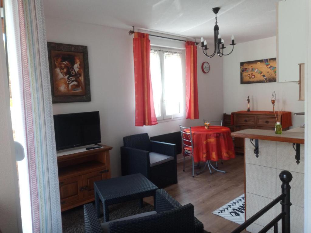 ein Wohnzimmer mit einem TV und einem Esstisch in der Unterkunft Park de Vincennes in Pau