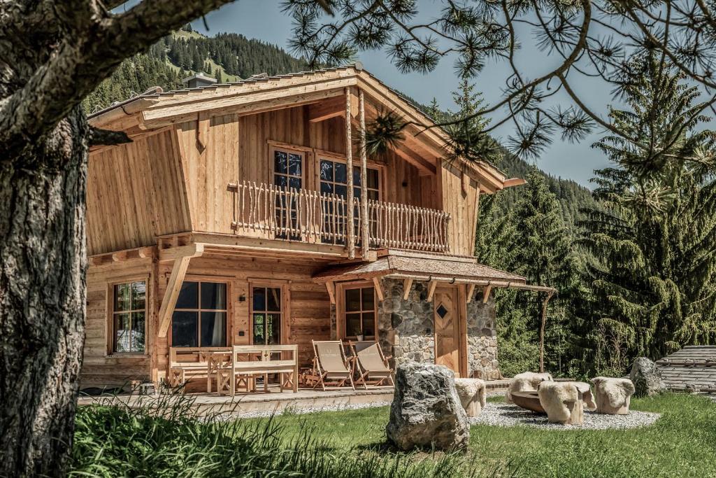 a log cabin with a wrap around porch and a deck at Benglerwald Berg Chaletdorf in Bach