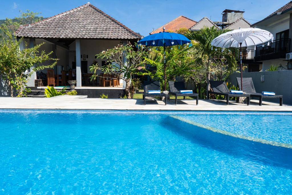 a swimming pool with two umbrellas and a house at Bali Dive Resort Amed in Amed