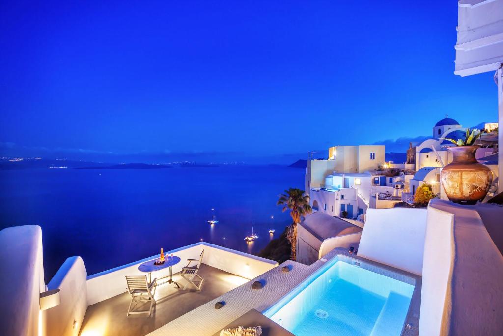 a swimming pool on the balcony of a house at night at Diamond Luxury Suites in Oia
