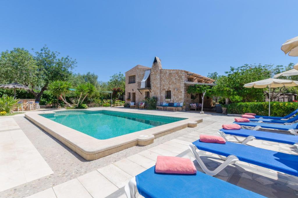 une piscine avec des chaises longues bleues et une maison dans l'établissement Can Rosillo, à Llucmajor