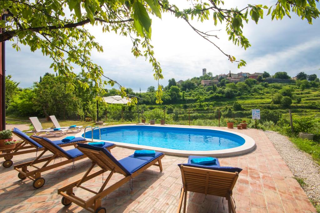 an outdoor swimming pool with chairs and a table at Villa Mamma Mia Oprtalj in Oprtalj
