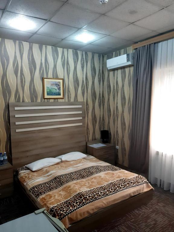 ein Schlafzimmer mit einem Bett in einem Zimmer mit einer Wand in der Unterkunft AZPETROL HOTEL GAZAX in Qazax