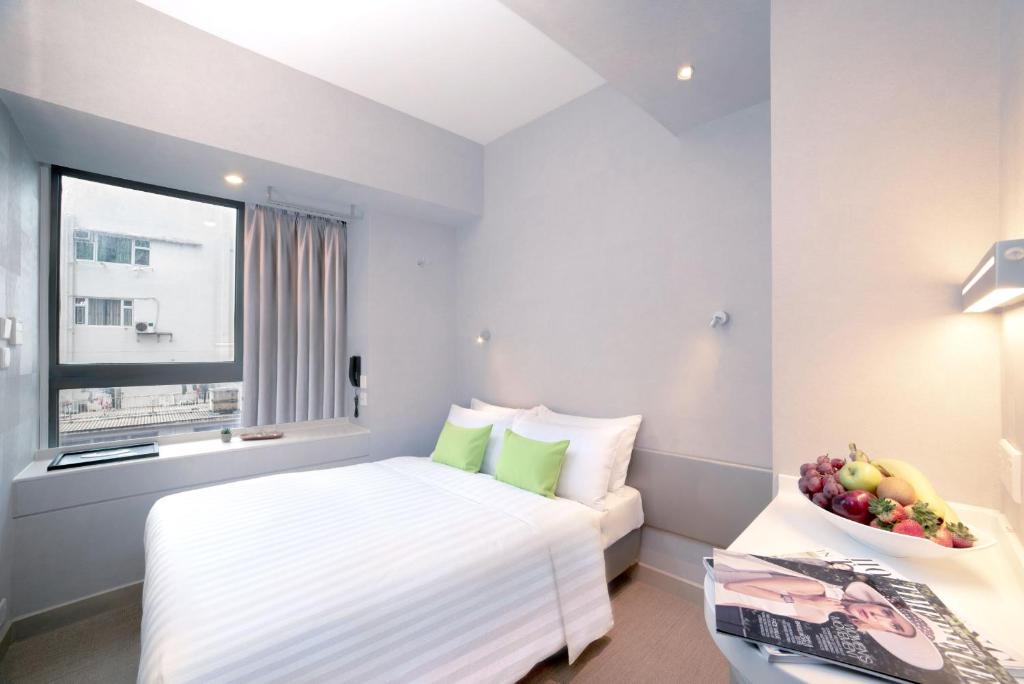 a hotel room with a bed and a bowl of fruit on a table at Hotel Ease Mong Kok in Hong Kong