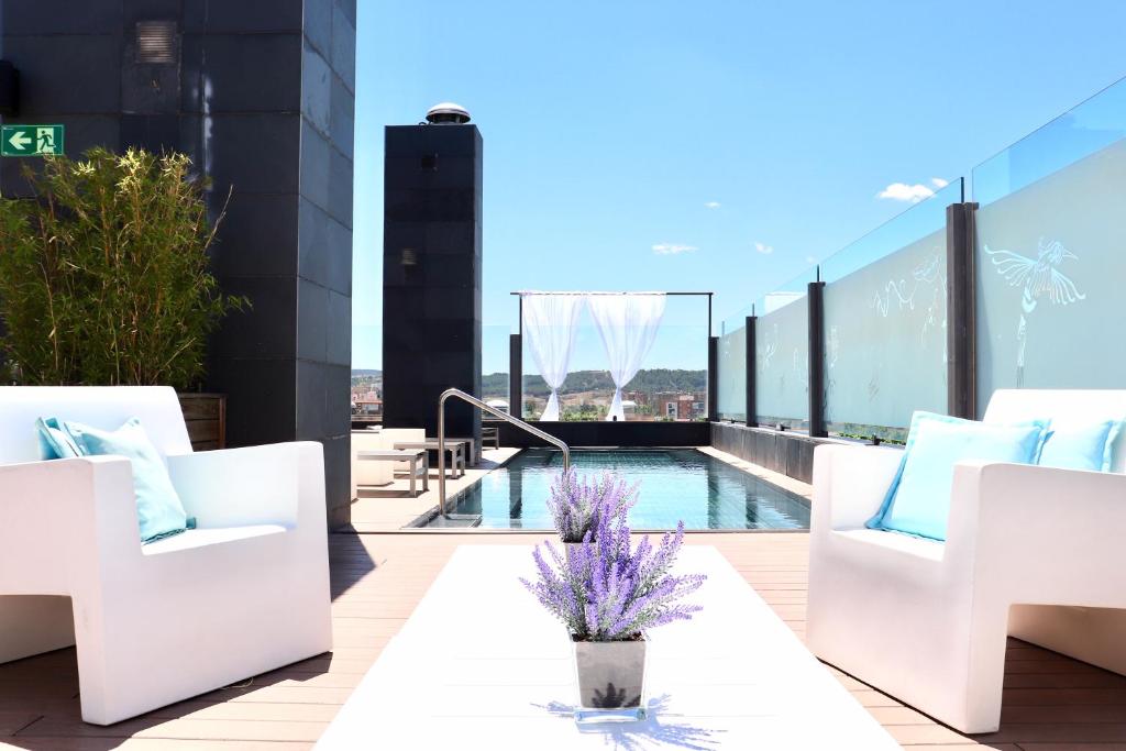 a balcony with white chairs and a swimming pool at PCM Forum Alcalá in Alcalá de Henares