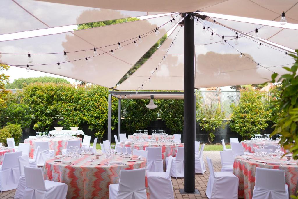 a set of tables and chairs under a white umbrella at PCM Forum Alcalá in Alcalá de Henares