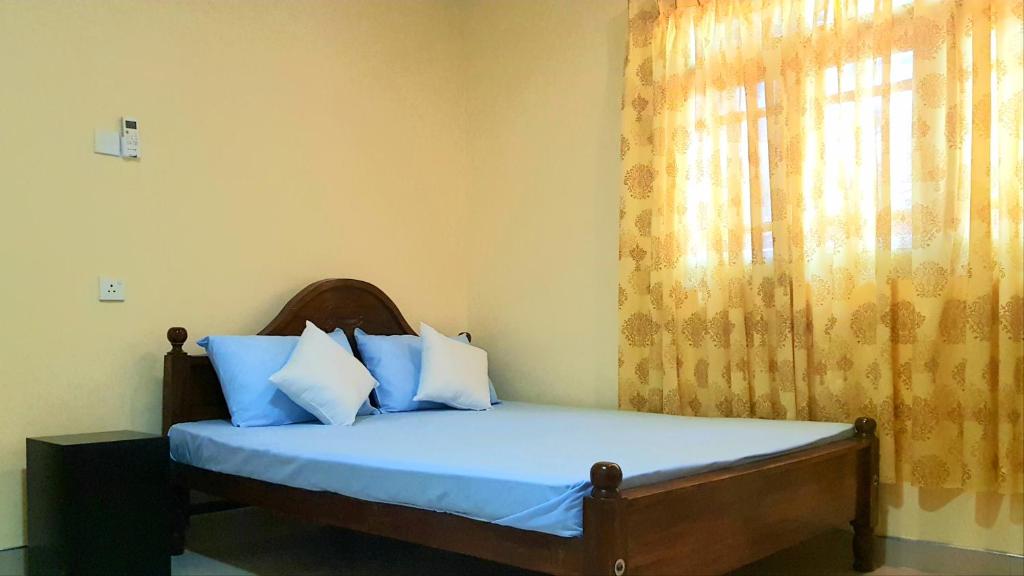 Schlafzimmer mit einem Bett mit blauer Bettwäsche und einem Fenster in der Unterkunft Nimal's Home in Anuradhapura
