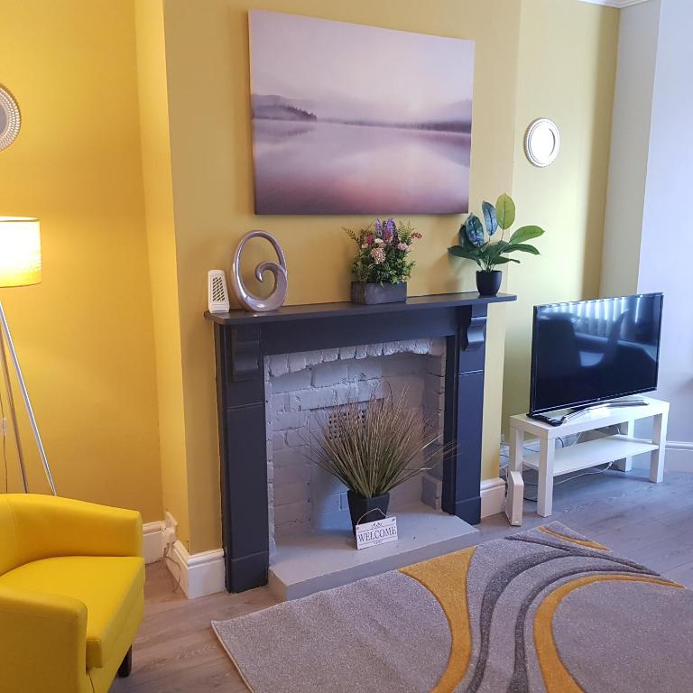 a living room with a fireplace and a tv at Hollis House in Derby