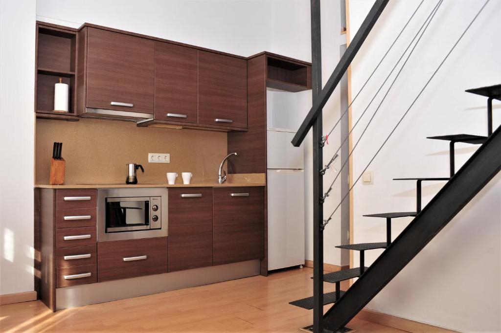 una cocina con armarios de madera y una escalera en Apartamentos Bejar en Barcelona