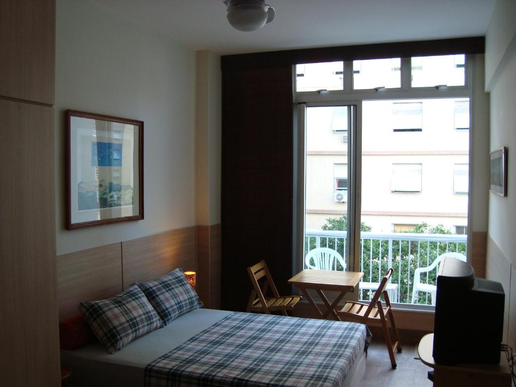 Schlafzimmer mit einem Bett, einem Tisch und einem Fenster in der Unterkunft Alex Rio Flats Studio with Balcony in Rio de Janeiro