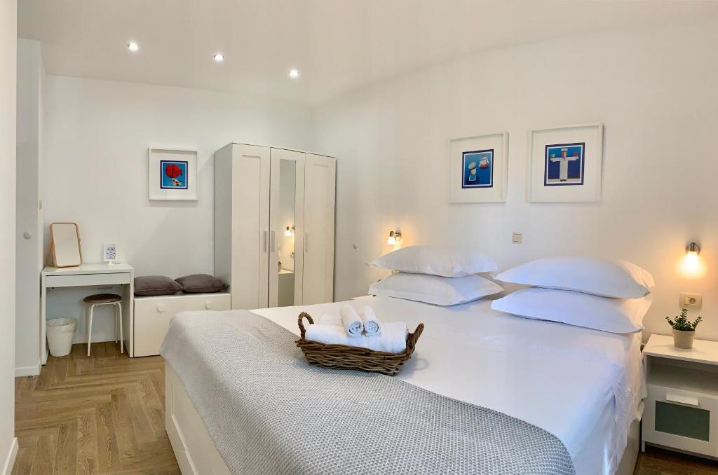 - une chambre blanche avec un lit et un panier dans l'établissement 17 Pines, à Makarska