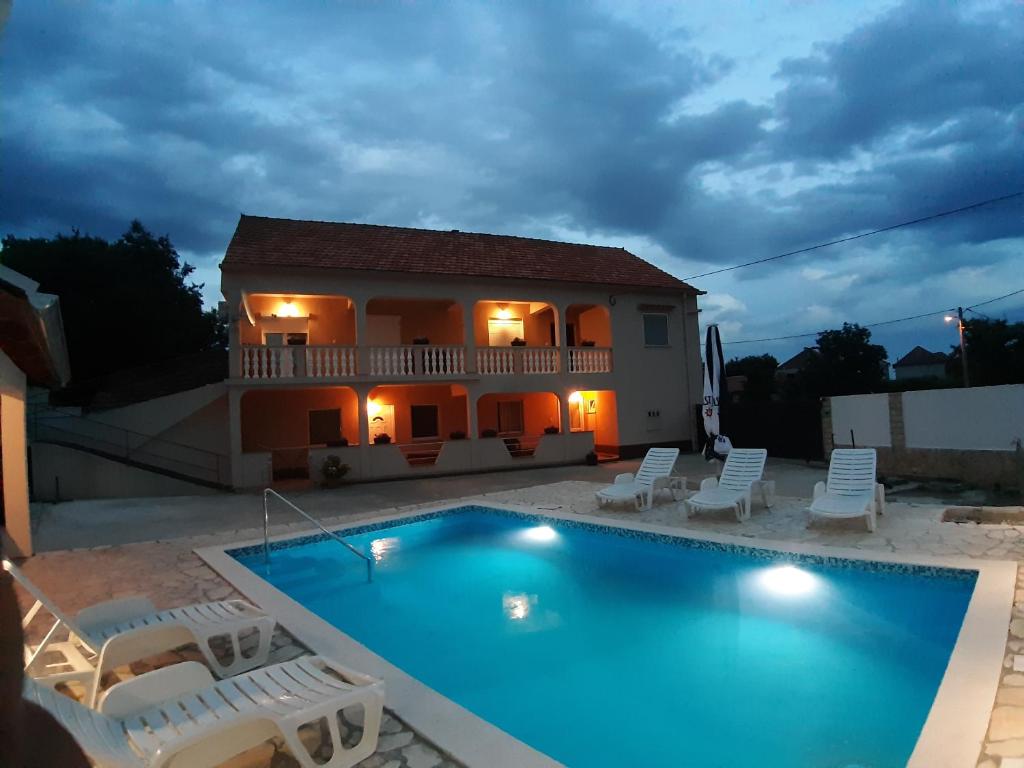 a villa with a swimming pool in front of a house at Apartment Elena in Galovac