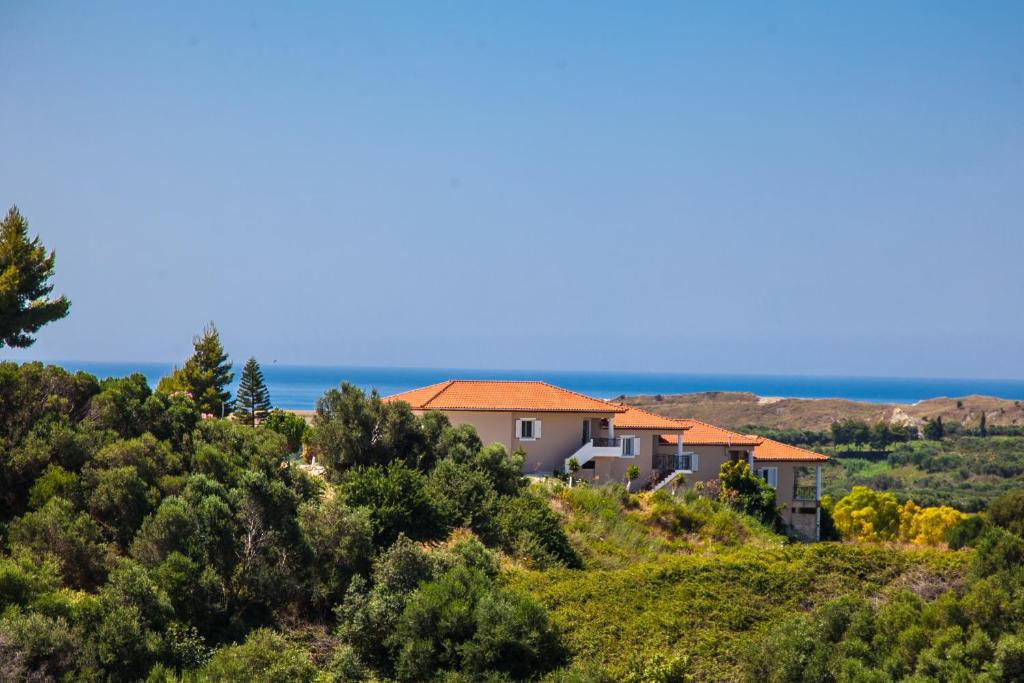 a house on a hill with the ocean in the background at Maspali Apartments in Lixouri