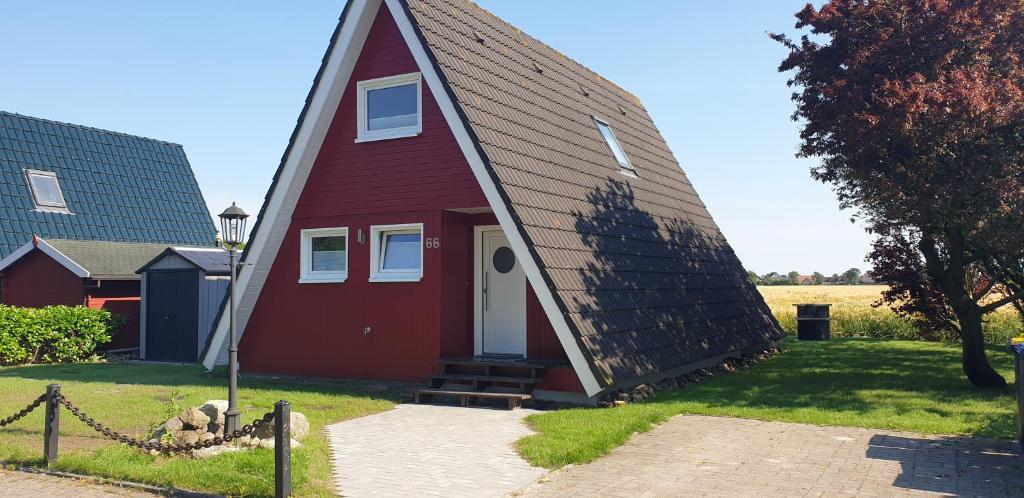 um pequeno celeiro vermelho com um telhado de gambrel em Murmel 3 - Strandkorb, Wallbox, WLan, Kamin em Carolinensiel