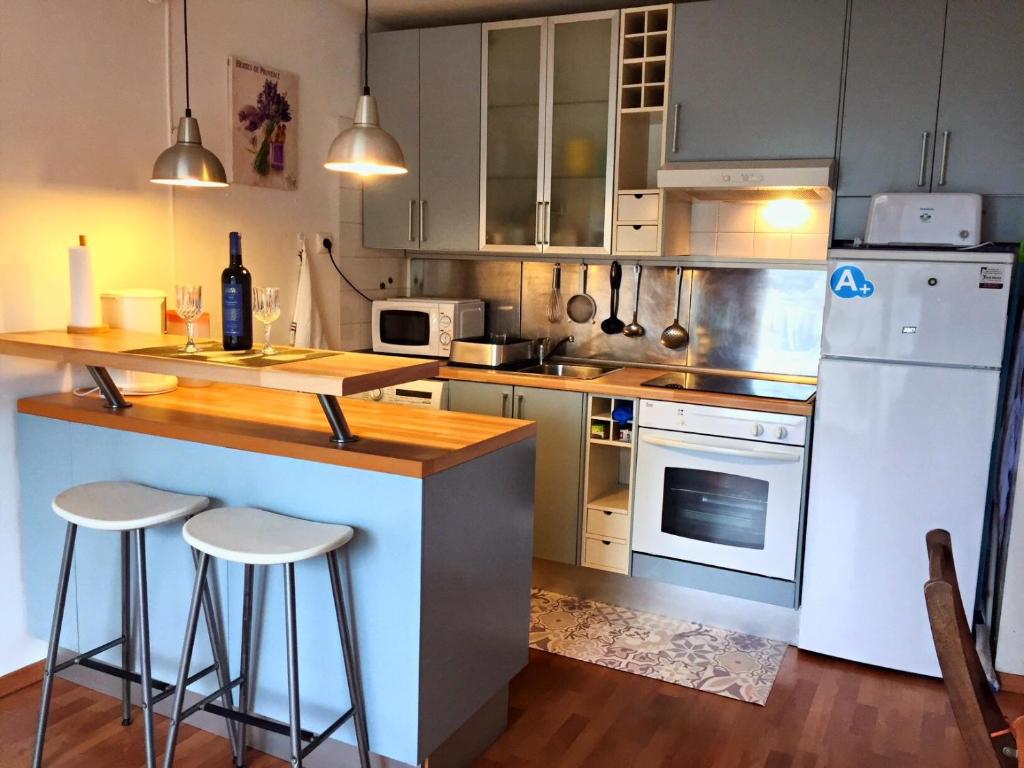 una cucina con frigorifero bianco e bancone con sgabelli di Appartement tranquille Sitges 5km a Sant Pere de Ribes