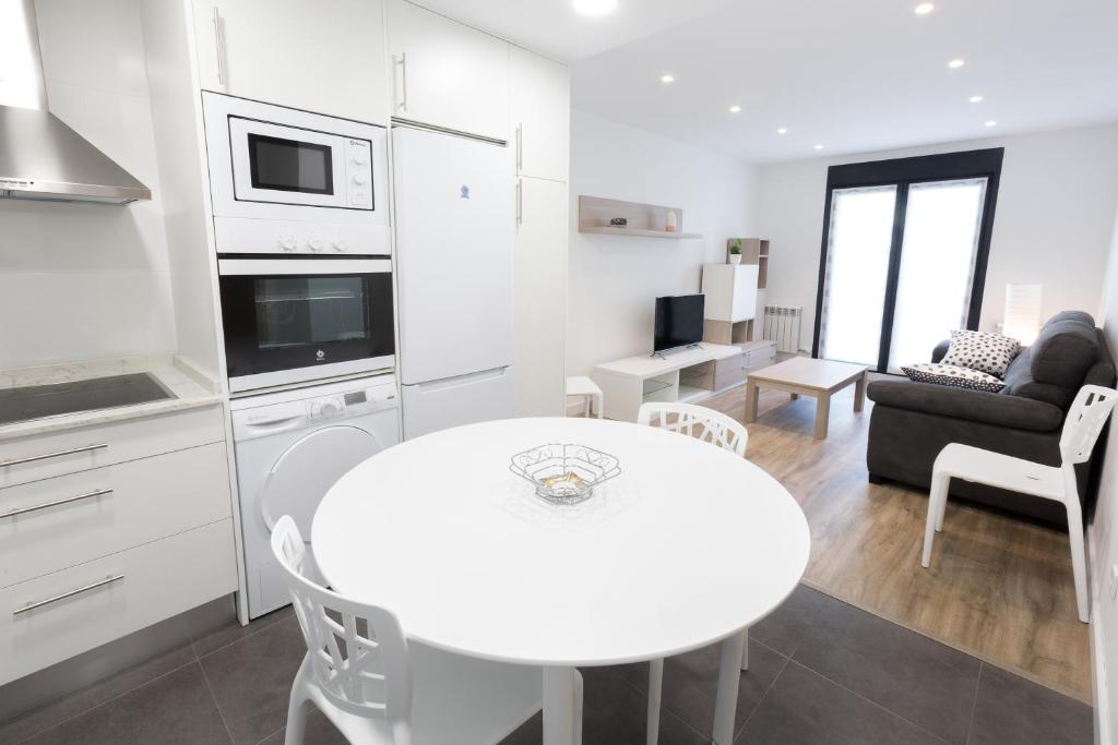 a white kitchen with a table and a living room at Apartamentos LA CATEDRAL 1ºA in Logroño