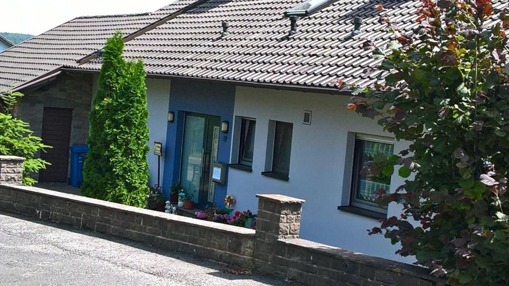 Casa blanca con puerta y ventanas azules en Ferienwohnung-Anja, en Fladungen