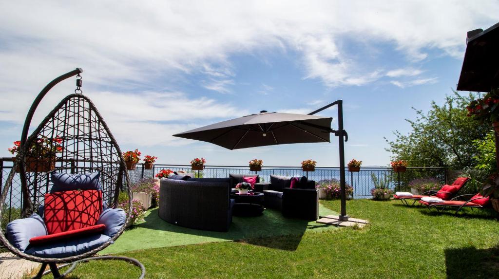 a patio with chairs and an umbrella on the grass at Apartman Nicole in Mošćenička Draga