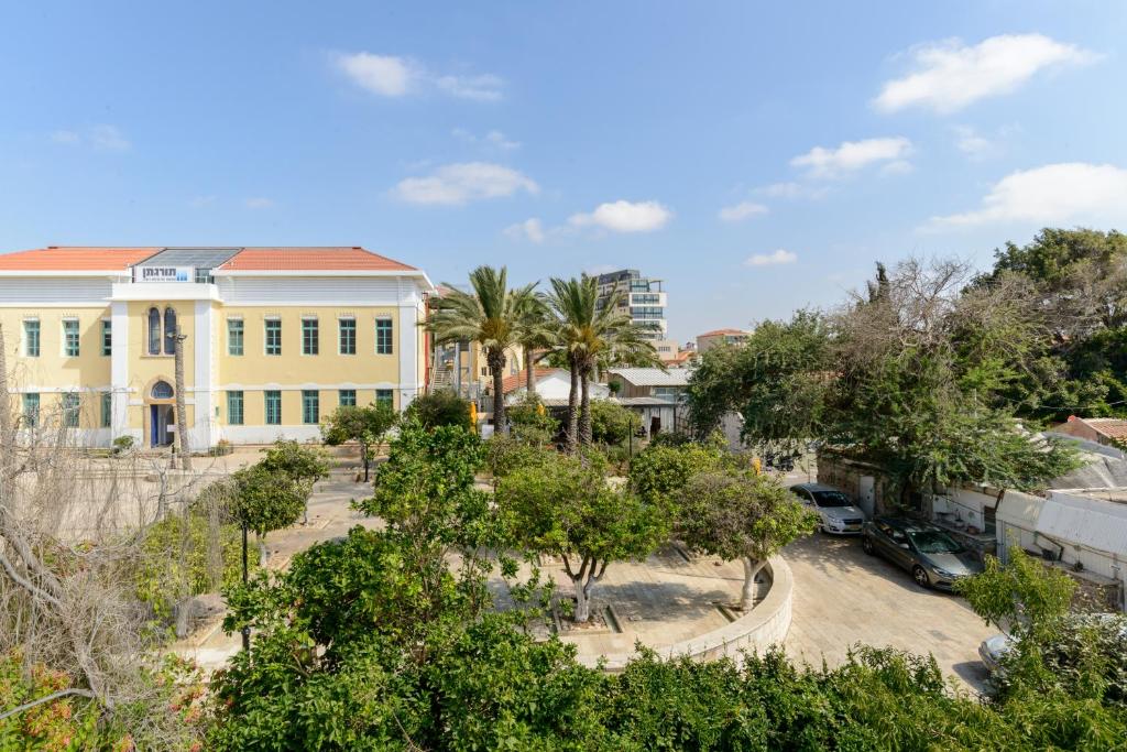 a yellow building with cars parked in a parking lot at High Class next to Susan Dallal by FeelHome in Tel Aviv