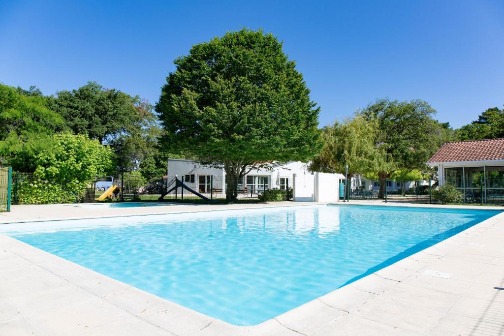 uma piscina com uma árvore e uma casa em Cap Océan em Seignosse