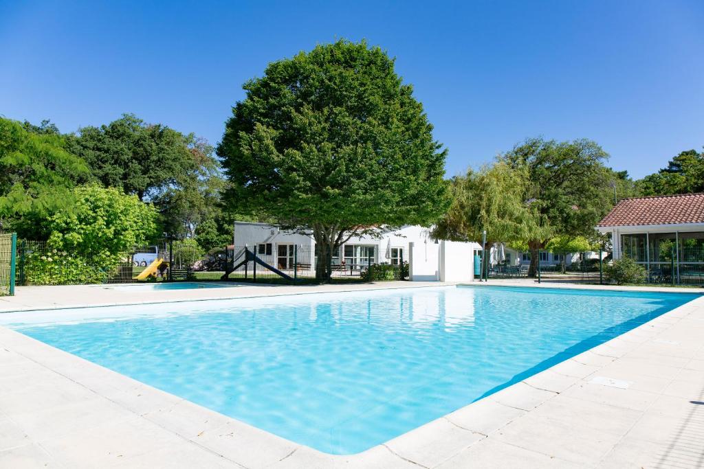 a swimming pool with a tree and a house at Cap Océan in Seignosse