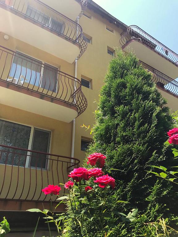 a building with a tree and red flowers in front of it at Guest House Villa Rose in Primorsko