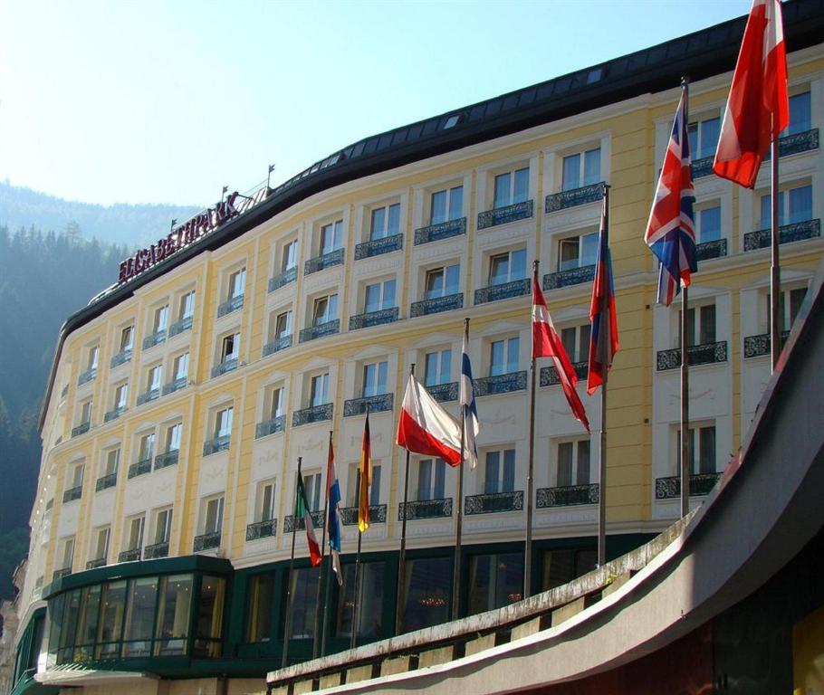 un edificio con un montón de banderas delante de él en Thermal Resort Hotel Elisabethpark, en Bad Gastein