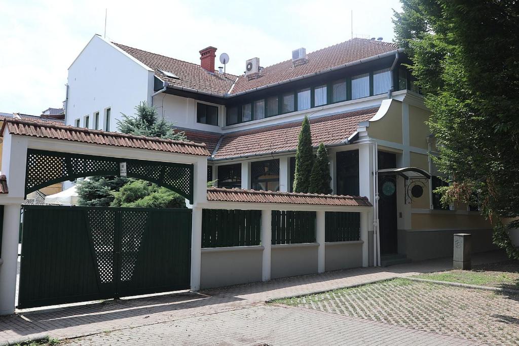 a large house with a green gate in front of it at Szlovák Panzió in Békéscsaba