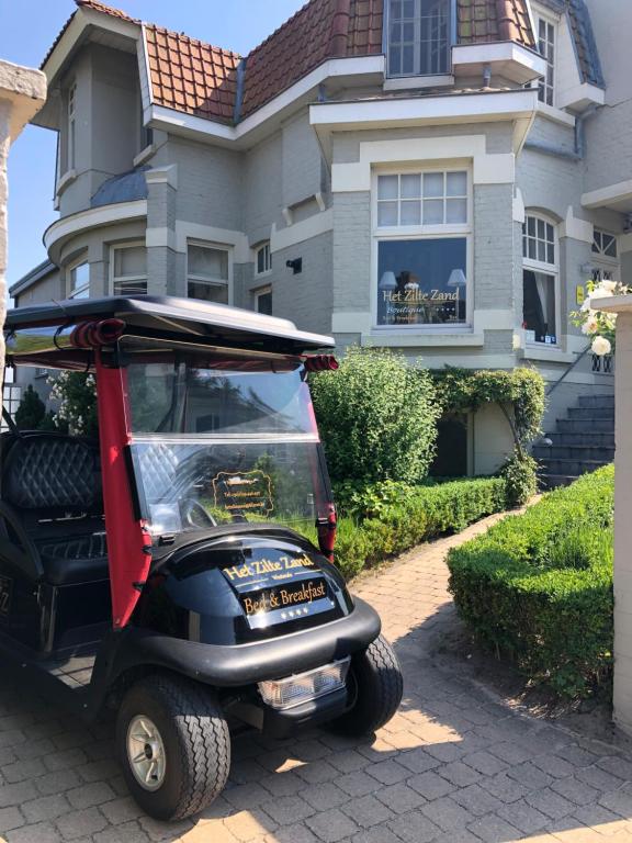 une voiturette de golf garée devant une maison dans l'établissement Bed & Breakfast Het Zilte Zand - Westende - Middelkerke - De Kust, à Middelkerke