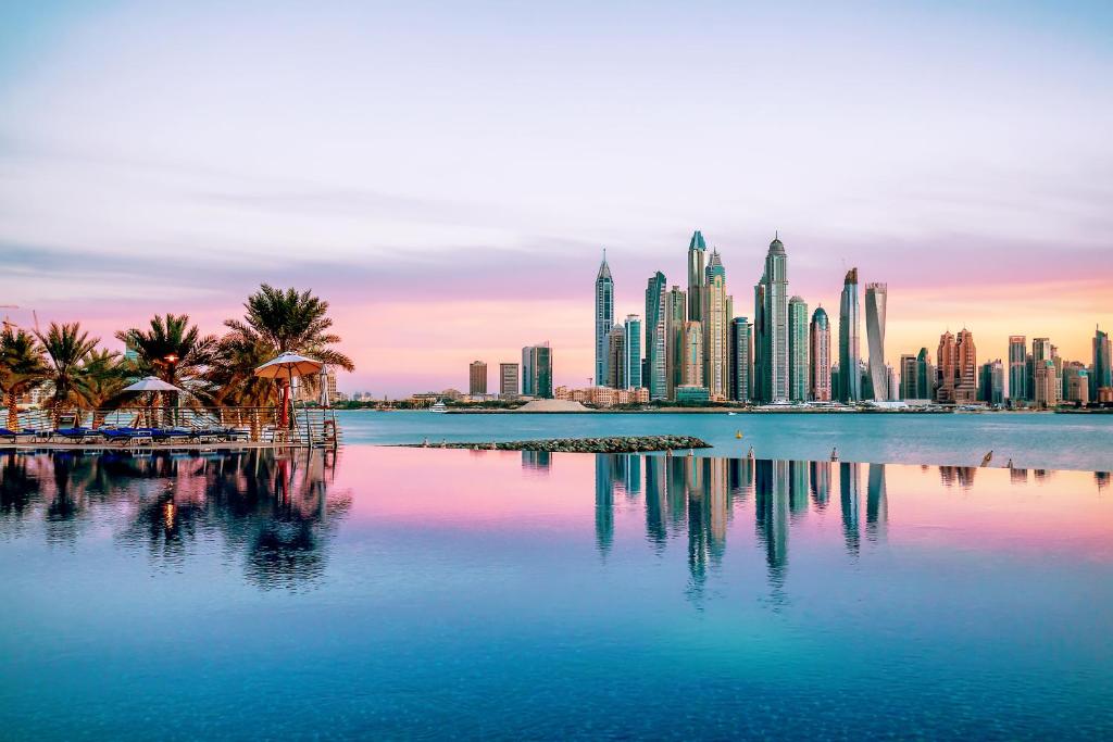 Dukes The Palm, a Royal Hideaway Hotel في دبي: أفق مدينة بها أشجار النخيل والمباني
