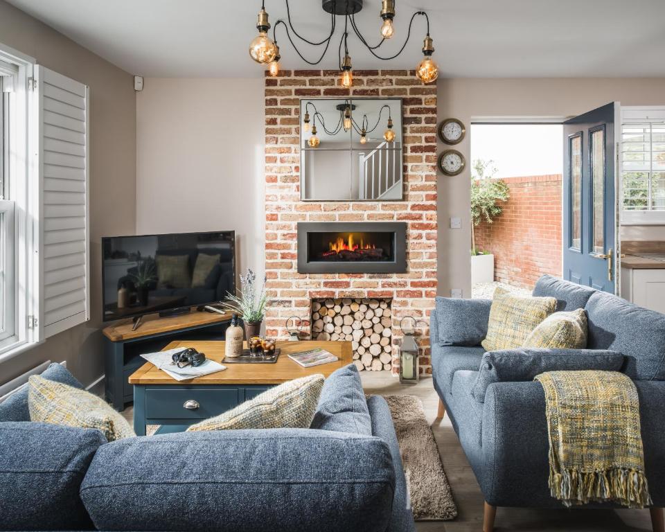 a living room with blue couches and a fireplace at Owlers Cottage in Camber