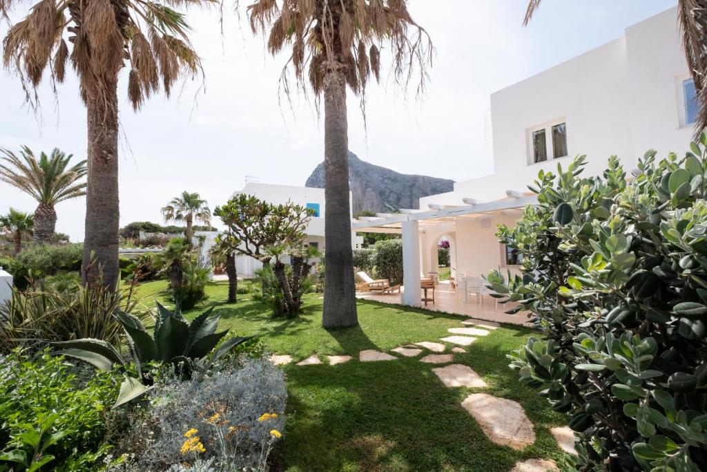 un jardin avec des palmiers et une maison dans l'établissement Villa Acquamarina sul mare, à San Vito Lo Capo