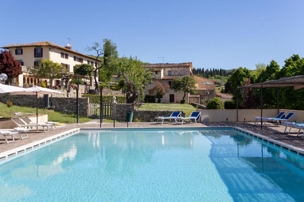 une grande piscine avec des chaises et une maison dans l'établissement Casafrassi, à Castellina in Chianti