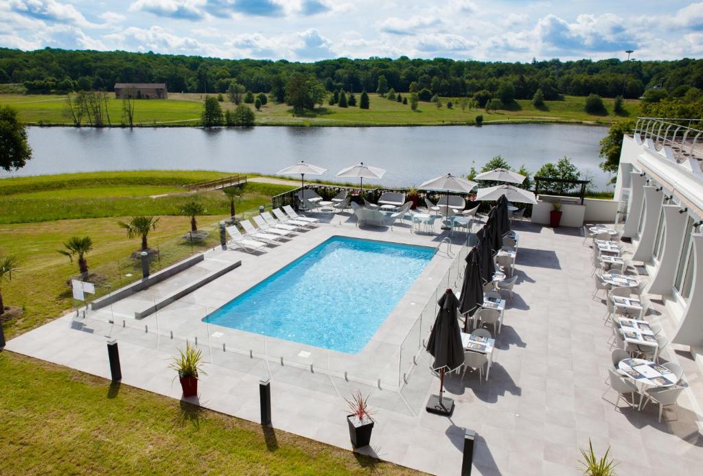 - une vue aérienne sur une piscine avec des chaises et un lac dans l'établissement Novotel Limoges Le Lac, à Limoges