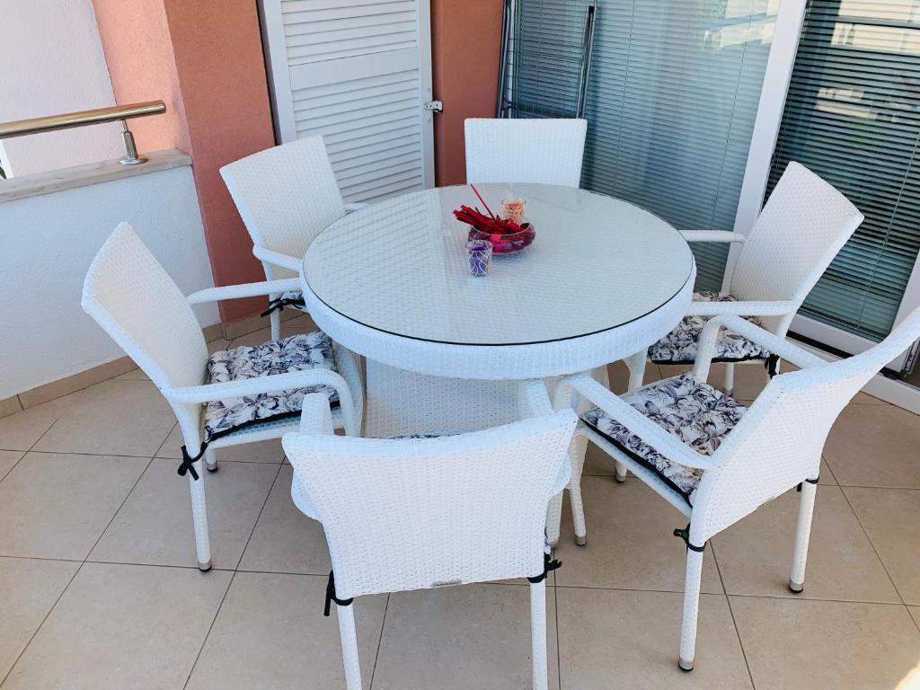 - une table et des chaises blanches avec un bol de fleurs dans l'établissement Josip Modern Apartment Novalja, à Novalja