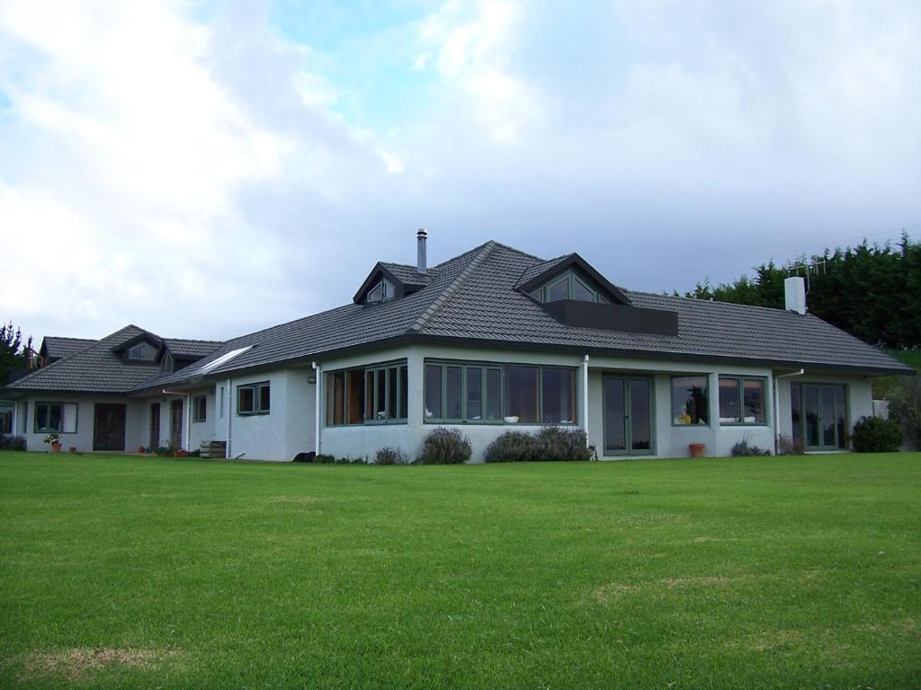 uma casa com um relvado verde em frente em Waiwurrie Coastal Farm Lodge em Mahinepua