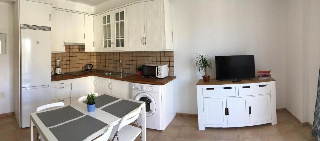 a kitchen with white cabinets and a table and a microwave at Charco Las Damas in Playa de San Juan