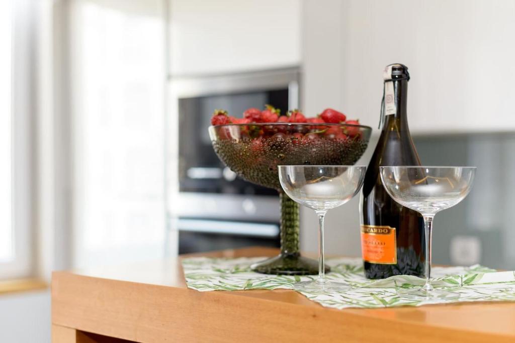 a table with two wine glasses and a bowl of fruit at Dąbrowskiego Apartment in Poznań