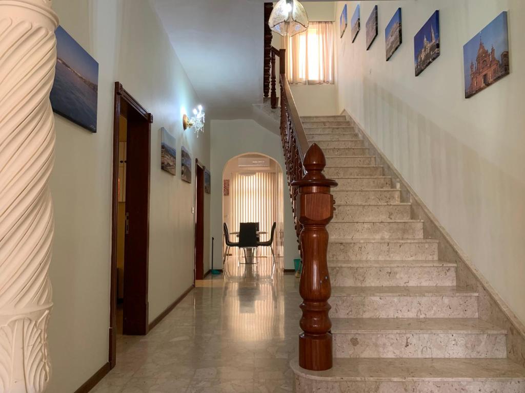 a hallway with stairs and a stair case with paintings on the walls at Cloud 9 Residence in Għajnsielem