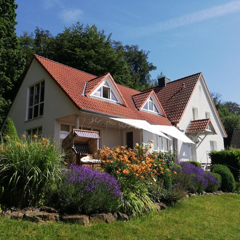 a white house with a red roof and some flowers at Ferienwohnung am Benther Berg in Gehrden