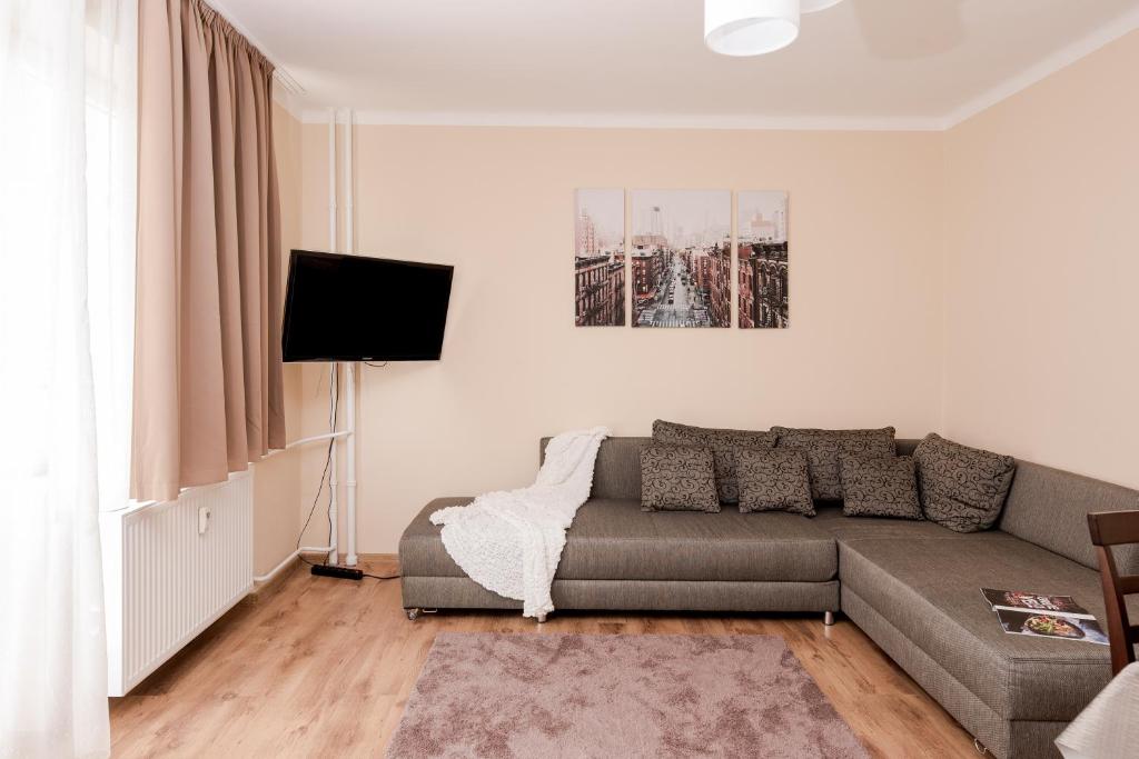 een woonkamer met een bank en een flatscreen-tv bij Better than Home in Boedapest