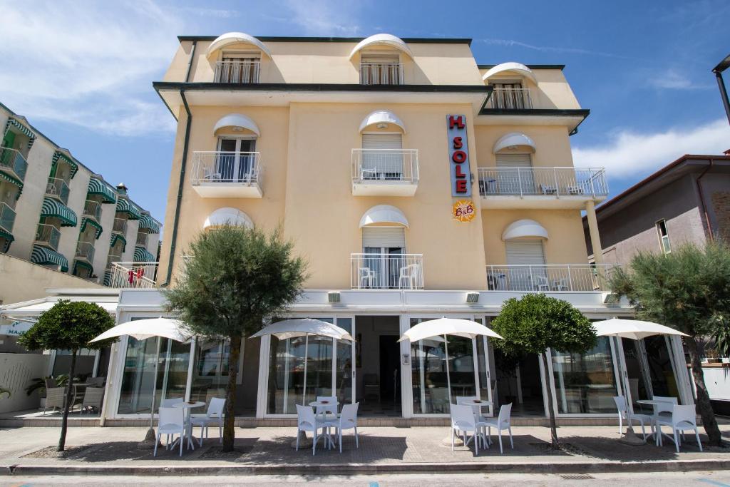 een gebouw met stoelen en parasols ervoor bij Hotel B&B Sole in Senigallia