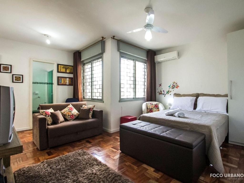 um quarto com uma cama, um sofá e uma televisão em Mariano - JK pertinho de tudo! em Porto Alegre