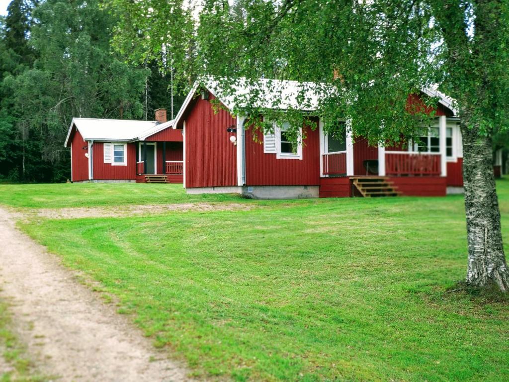uma casa vermelha com uma árvore em frente em Klarälvsbyn em Sysslebäck